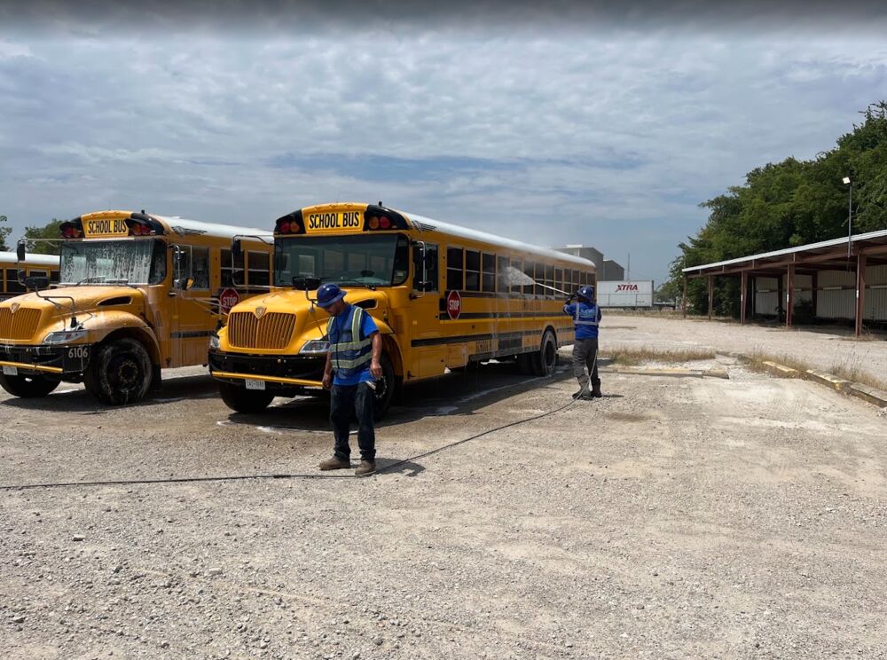 Crew washing two school buses on a district lot
