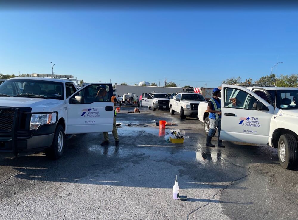 Crew detailing several Texas Department of Transportation trucks with doors open