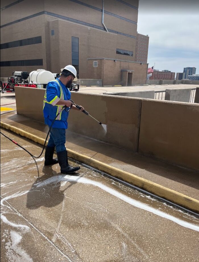 Crew member applying cleaning foam to a concrete garage wall