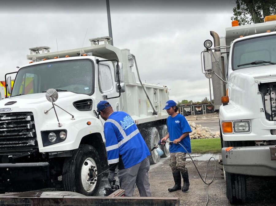 Crew washing a white dump truck with a foam cannon